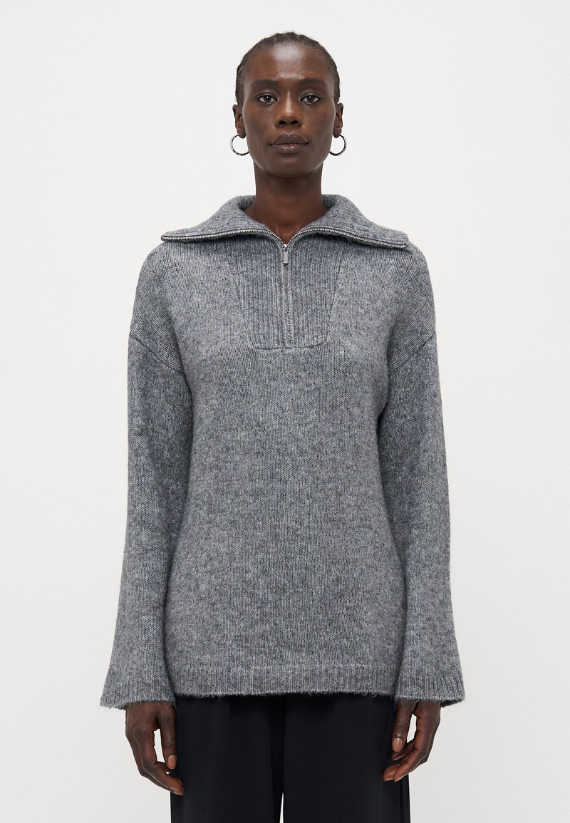 Maglione grigio a maglia con colletto a mezza zip, dettagli a coste sul petto e maniche ampie. Morbido al tatto e con una vestibilità comoda.