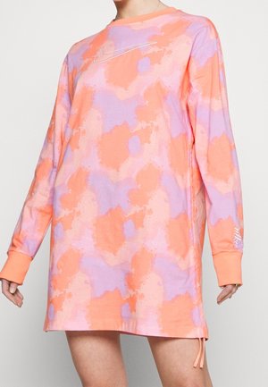 Sukienka Nike z długim rękawem w pomarańczowo-fioletowy wzór tie-dye, haftowany znak Swoosh na piersi oraz logo Nike na mankiecie lewej rękawa.