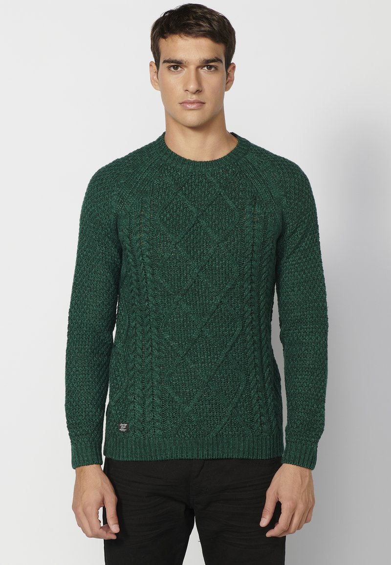 Groene gebreide trui met een getextureerd ontwerp en ruitpatronen, geribbelde manchetten en een ronde hals. Dikke, gezellige stof.