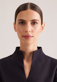 Indumento con collo navy dal design elegante, caratterizzato da una scollatura alta e dettagli minimalisti, realizzato in un tessuto liscio e opaco.