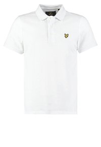 Polo blanc en coton, doté d'un col classique, d'une patte de boutonnage à trois boutons et d'un logo brodé jaune sur la poitrine gauche.
