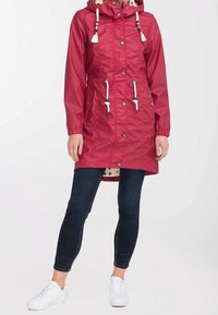 Red, waterproof parka with a hood, drawstrings, and decorative beads. Features two front pockets and a patterned inner lining. White accents.