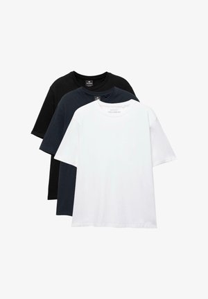 Három egyszerű, kerek nyakú póló fekete, tengerészkék és fehér színekben, egymásra helyezve, az első fehér pólóval.