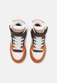 Sneakers de cano alto com uma língua de malha branca, detalhes em camurça laranja e castanha, painéis em pele branca e sola de borracha. Logótipo da Kickers visível.