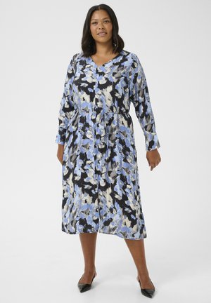 Robe fleurie avec des motifs bleus, noirs et blancs. Manches longues, décolleté en V, taille cintrée et coupe mi-longue. Texture de tissu lisse.