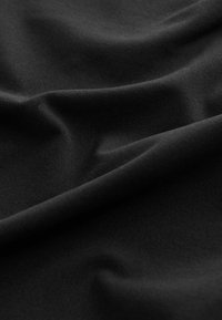 Schwarzer Stoff mit glatter Textur, der sanfte Falten und subtile Knicke aufweist und eine einheitliche Farbe ohne Muster oder auffällige Hardware zeigt.