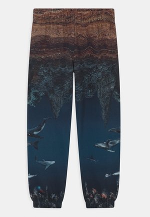 Hose mit Unterwasser-Szenenprint, der Wale, Haie und ozeanische Höhlenformationen in dunkelblauen und braunen Tönen zeigt.