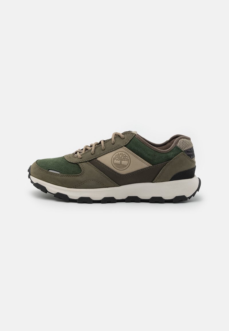 Scarpa sportiva verde e marrone caratterizzata da materiali in suede e tessuto, una suola ammortizzata, design con lacci e un dettaglio del logo ben visibile.