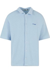 Light blue short-sleeve shirt, ribbed texture, button closure, contrasting collar, features embroidered "Prohibited" logo in blue.