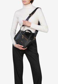 Borsa a tracolla in pelle nera con manico superiore e tracolla removibile, tasca frontale con zip e accessori in metallo color oro.