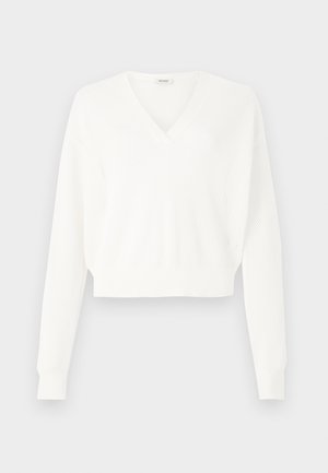 Bela skrajšana pulover s peto zasnovo, izdelana iz teksturirane mrežaste tkanine, s dolgimi rokavi in ribastimi manšeti.