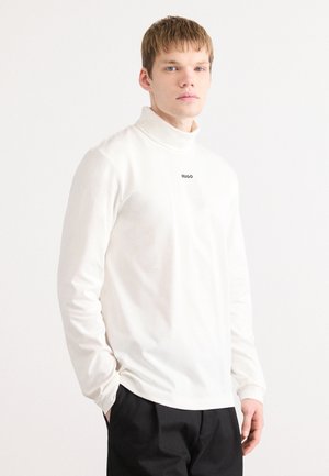 White long-sleeve turtleneck shirt with black "HUGO" logo on the chest, made of soft fabric, features a fitted design and minimal seam detail.