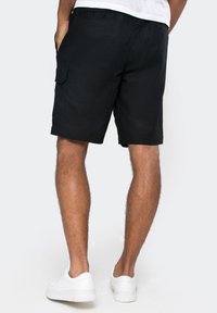 Black cargo shorts made of lightweight fabric with a relaxed fit, featuring side pockets and a flat waistband. Worn with white sneakers.