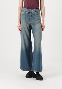 Lichtblauwe wijde denim jeans met een ceintuur, voorzakken en een geleidelijke kleurverloop van boven naar beneden.