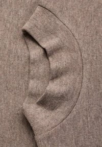 Tessuto a coste marrone con una consistenza morbida, caratterizzato da un design a risvolto. Le cuciture sono visibili, aggiungendo particolari all'aspetto complessivo.