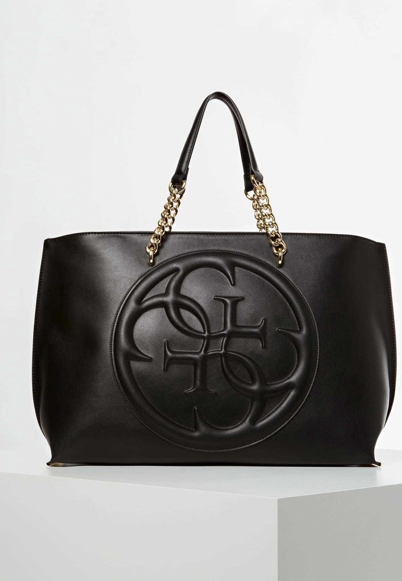 Zwarte leren totebag met een groot geaderd logo, een gladde textuur, gouden kettingaccenten aan de handvatten en een gestructureerde vorm.