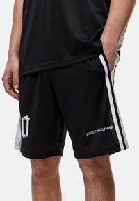 Basketbalshorts van zwart ademend meshmateriaal met witte zijstrepen; voorzien van 'GOODFORNOTHING' branding en een onderscheidend logo.
