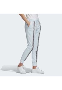 Ljusblåa sweatpants med svarta sidostråk som pryds av logotext, elastiska muddar och dragsko i midjan. Mjuk, strukturerad tyg.