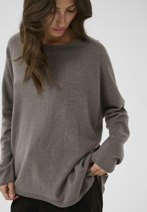 Light brown sweater in soft knit fabric, featuring a rounded neckline, long sleeves, and side slits at the hem for ease of movement.