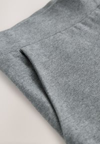 Tessuto grigio piegato, che mette in mostra una texture morbida con una finitura liscia. Il materiale appare leggero e informale, adatto per l'abbigliamento quotidiano.