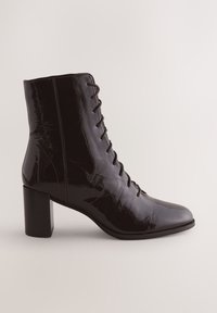 Sort ankelstøvle i laklæder med rundet tå, snørebånd foran og en chunky, høj blokhæl. Glat, skinnende overflade med subtil tekstur.