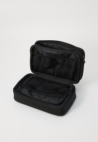 Black travel pouch with zipper, featuring a mesh pocket and two compartments. Made of durable fabric with a smooth texture.