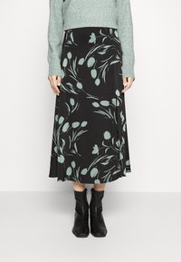 Černá midi sukně s květinovým vzorem v jemné zelené barvě, vyrobená z hladké látky. Má volný střih a rozšířený tvar, nosí se s černými botami.