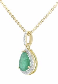 Zlata verižica z obeskom iz smaragda v obliki kapljice, obkroženim z majhnimi prozornimi kamni v srebrni nastavitvi, ki ustvarja kontrast v barvi in teksturi.