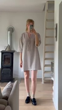 Vestido às riscas com um corte solto, até ao joelho, mangas curtas e decote com meia abotoação. Usado com sapatos de estilo loafers pretos e meias até ao tornozelo.