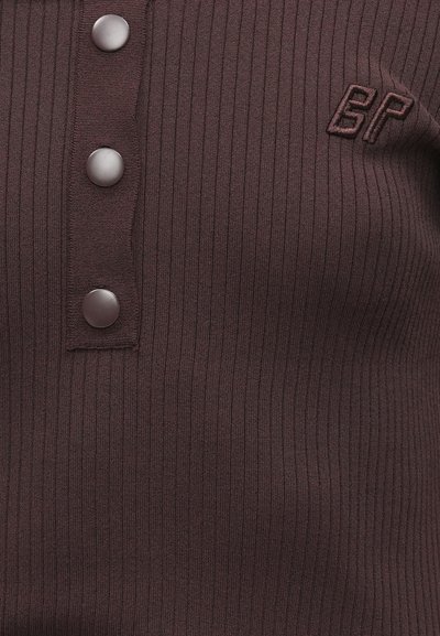 Μπορντό κορδωτό ύφασμα τοπ με πατιλέτα κουμπιών που διαθέτει τρία μεταλλικά κουμπιά και κεντημένη λεπτομέρεια λογότυπου στην αριστερή πλευρά.