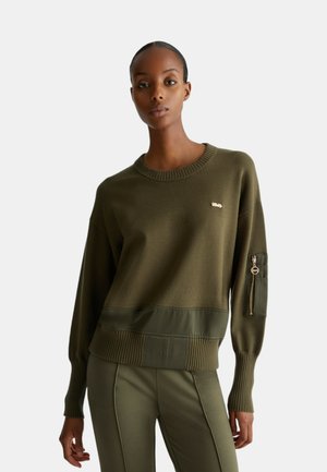 Maglione verde oliva con colletto e polsini a costine, caratterizzato da un pannello di raso liscio all'orlo e una tasca con zip sul maniche.