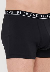 Schwarze Baumwollunterhose mit körpernaher Passform, ausgestattet mit einem elastischen Bund in Weiß mit Markenlogo. Schlichte, glatte Textur mit klassischem Schnitt.