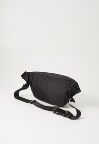 Black crossbody bag made of nylon, featuring a zippered main compartment, adjustable strap, and subtle embossed logo on the front.