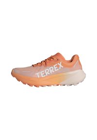 Oranžová bežecká obuv s sieťovaným zvrškom, výrazné biele logo "TERREX", textúrovaná podrážka a odpružená medzipodrážka pre podporu.