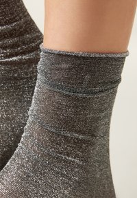 Metallic silver ankle socks featuring a textured, shimmering finish with gathered elastic at the top, designed for a snug fit.