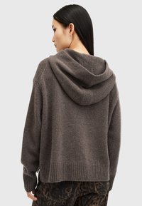 Felpa con cappuccio in morbido tessuto grigio, caratterizzata da una vestibilità comoda, polsini e orlo a costine, e una finitura strutturata. Indossata con pantaloni scuri a fantasia.
