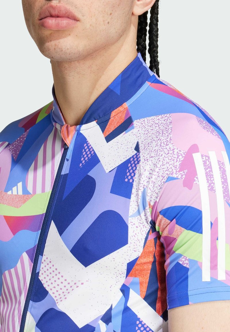 Jersey de ciclismo de manga corta con un patrón abstracto multicolor en tonos azul, rosa, verde y naranja; incluye una cremallera en la parte frontal.