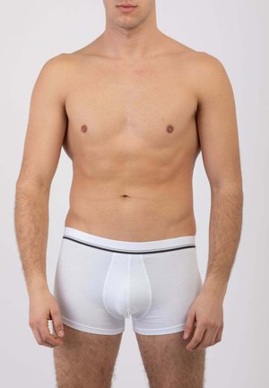 Boxer in cotone bianco con fascia elastica nera in vita, dotati di tasca frontale e vestibilità aderente, indossati da un modello maschile.
