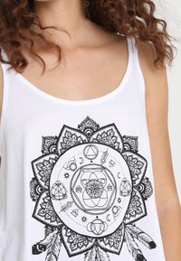 Débardeur blanc orné d'un motif mandala noir avec des motifs complexes, des formes géométriques et des accents de plumes en bas.