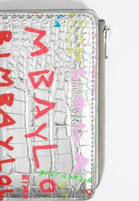 Silver, crocodile-textured wallet featuring colorful, bold lettering and graphic elements. Includes a zipper closure and logo detail.