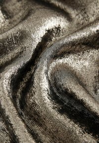 Metallic fabric with a smooth texture, featuring a shiny silver and gold blend. The surface has wrinkled folds, creating a dynamic appearance.