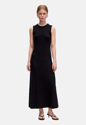 Zwarte mouwloze jurk met een textuur gebreide ontwerp, hoge halslijn en een volle lengte silhouet. Draag het met minimalistische zwarte haksandalen.