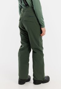 Zielone spodnie narciarskie z regulowanymi czarnymi szelkami, dwiema tylnymi kieszeniami i zwężanym krojem. Wykonane z teksturowanego, wodoodpornego materiału.