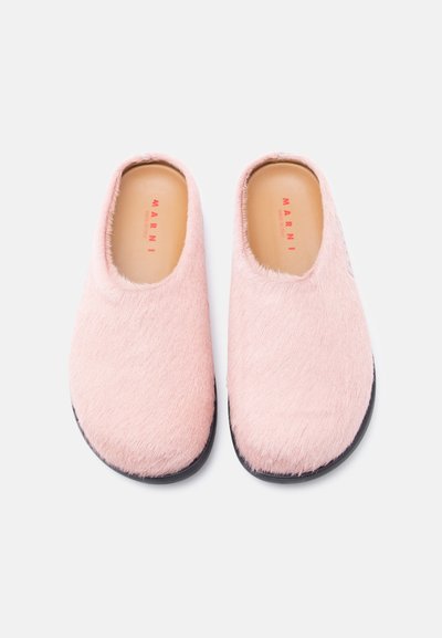 Ροζ παπούτσια χωρίς κορδόνια με γούνινη υφή, στρογγυλεμένη μύτη, μαύρη σόλα και μινιμαλιστικό σχέδιο. Εσωτερικά εμφανίζεται το "MARNI" τυπωμένο με κόκκινο σε μπεζ εσωτερική σόλα.