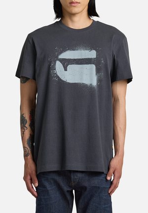 Camiseta de algodón gris oscuro con un diseño gráfico desgastado en azul claro en la parte frontal. Mangas cortas y escote redondo.
