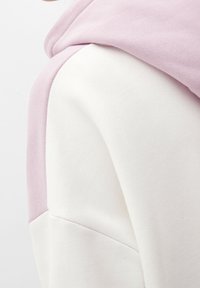 Hoodie rosa chiaro e bianco realizzato in un morbido misto cotone, con un design senza cuciture sulle spalle e un cappuccio testurizzato.