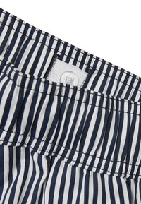 Navy ja valge triibuline kangas, millel on elastne ja nööbiga detail, pehme tekstuur ja korralik õmblus.