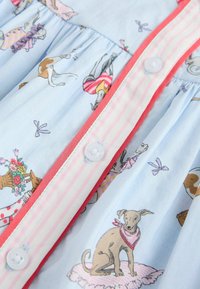 Svetlo modra tkanina z ilustracijami psov, ki nosijo šale in obleke, roza črtast knof placket z koralnim robom in belimi gumbi.