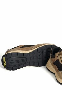 Un par de zapatillas Hoff MK II en beige y negro, que muestran una suela negra detallada con el logo amarillo de Hoff y texto visible en la suela exterior.