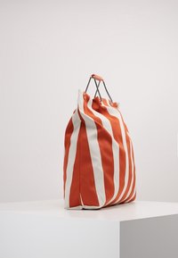 Borsa a spalla a righe arancioni e bianche realizzata in tessuto robusto. Presenta un bordo pieghevole e accessori in argento per le maniglie.